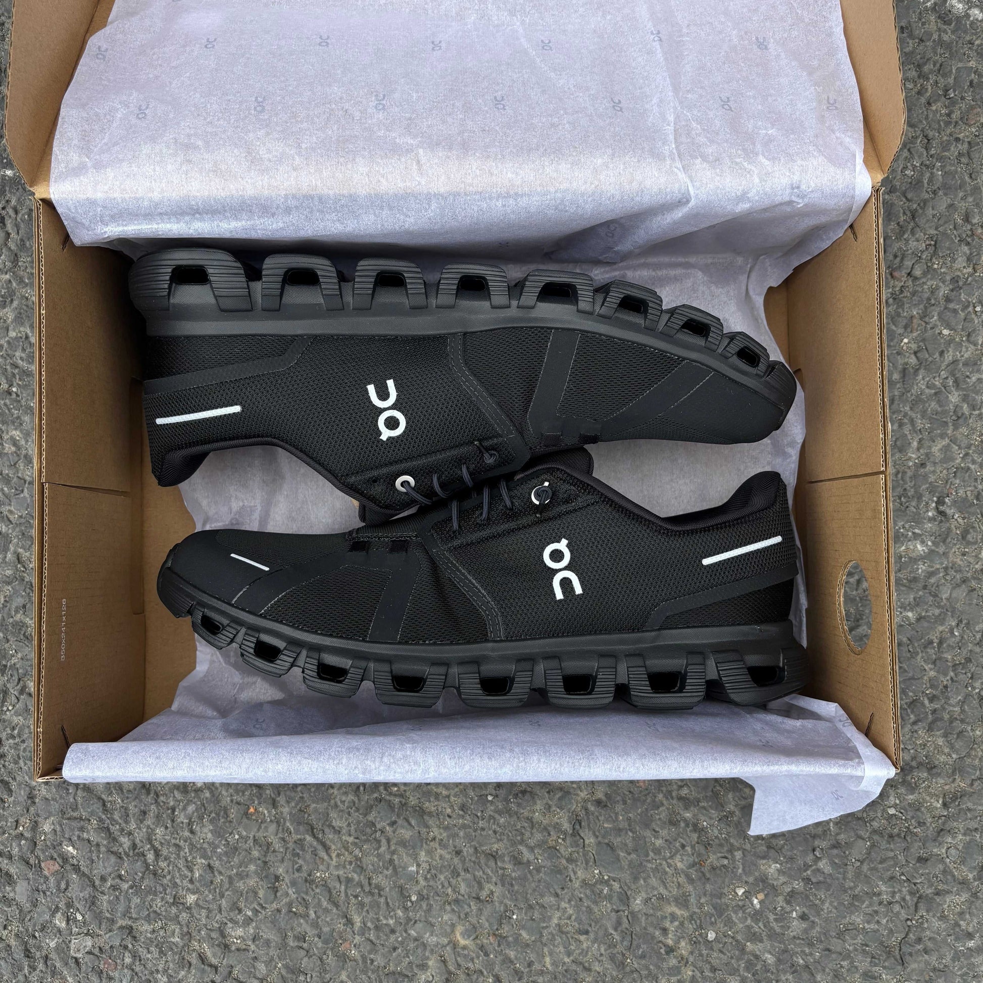 Black athletic shoes in a cardboard box with bubble wrap