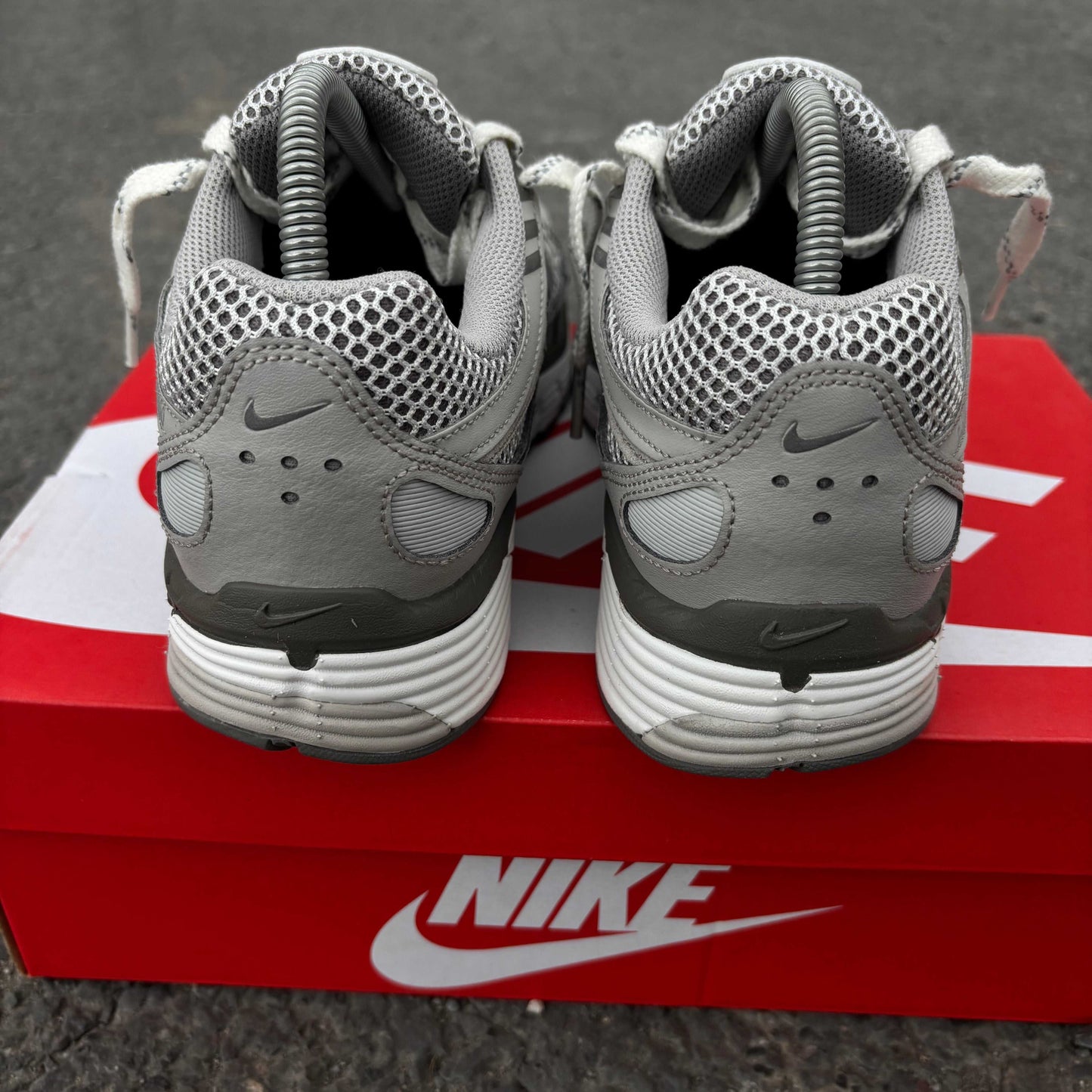 Gray Nike sneakers on a red Nike box with a dark background