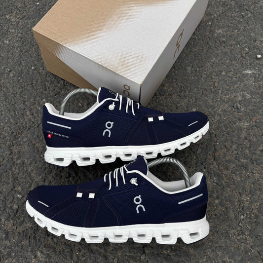 Navy running shoes with white soles on a gray surface